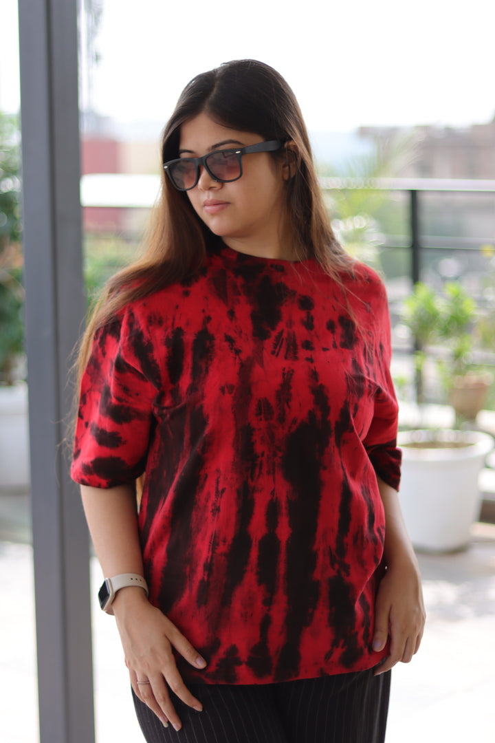 Woman wearing a red and black patterned top with sunglasses indoors.